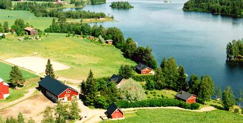 Ilmakuva Kotirinteen tilasta, punaisista rakennuksista ja järvestä
